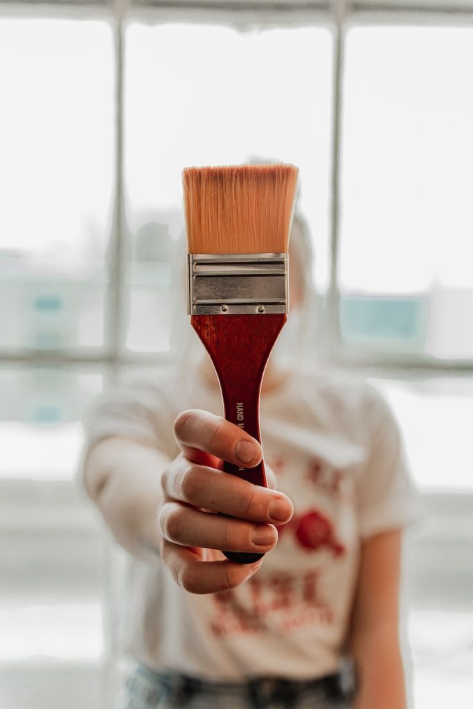 a woman holding a paint brush in her hand